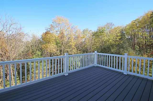 a balcony with wooden floor and trees in the background