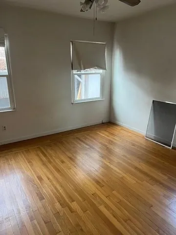 an empty room with wooden floor cabinet and windows