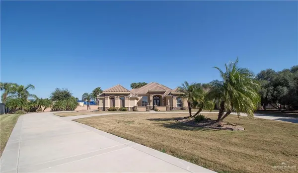 a view of a house with a yard and palm trees