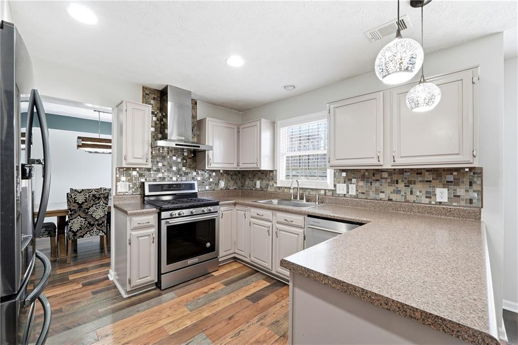 2964 Abbotts Oak Way Duluth, GA 30097 - Photo 16 of 29 a kitchen with stainless steel appliances granite countertop a stove a sink dishwasher and white cabinets with wooden floor