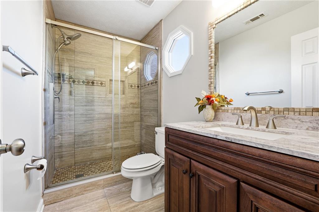 2964 Abbotts Oak Way Duluth, GA 30097 - Photo 24 of 29 a bathroom with a granite countertop sink a toilet and shower