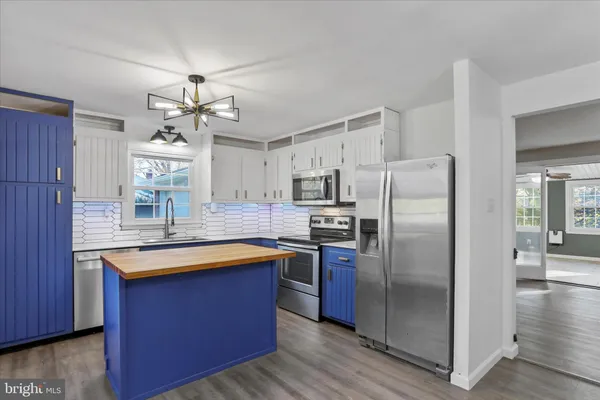 a kitchen with stainless steel appliances granite countertop a refrigerator a sink dishwasher a stove and a dining table with wooden floor