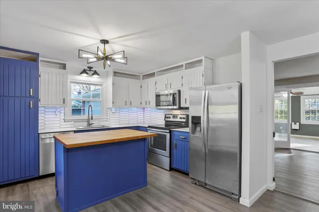 a kitchen with stainless steel appliances granite countertop a refrigerator a sink dishwasher a stove and a dining table with wooden floor