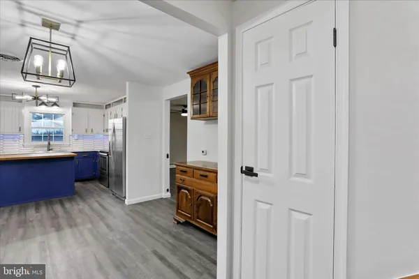 a view of a kitchen with stainless steel appliances wooden floor and more cabinets