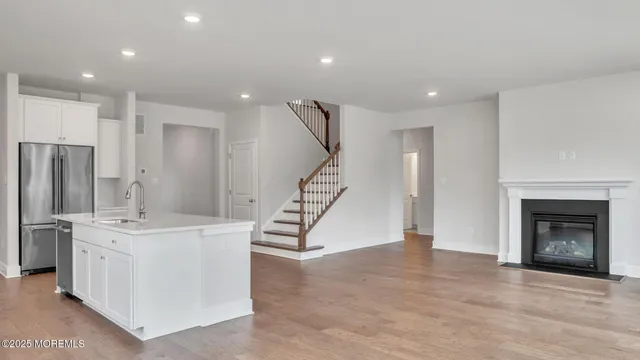 a view of a livingroom with furniture wooden floor fireplace and windows