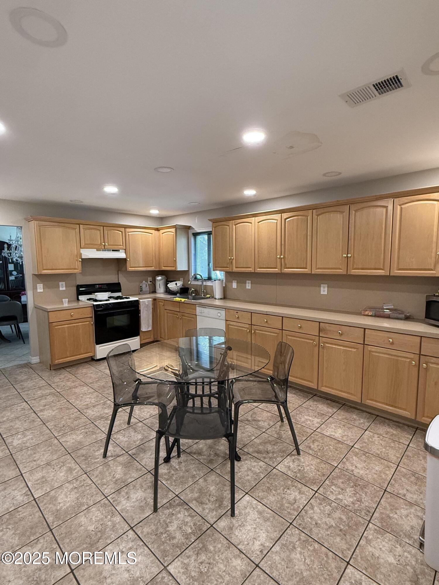 519 2nd Avenue Long Branch, NJ 07740 - Photo 8 of 24 a kitchen with a table chairs microwave and cabinets