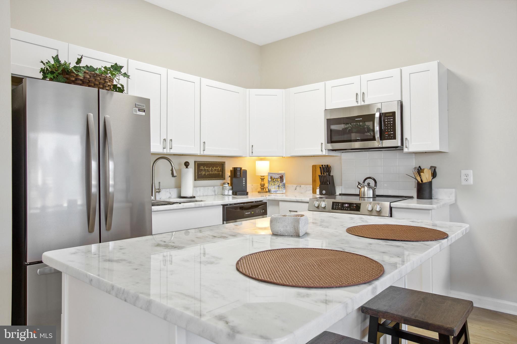 a kitchen with stainless steel appliances granite countertop a sink a microwave a refrigerator and white cabinets