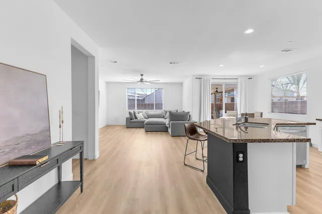 a kitchen with a sink dishwasher a stove and a dining table with wooden floor