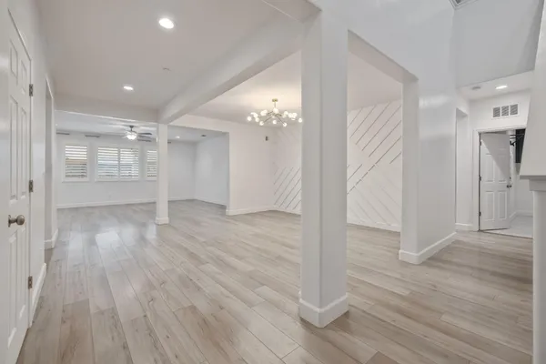 wooden floor in an empty room with a chandelier