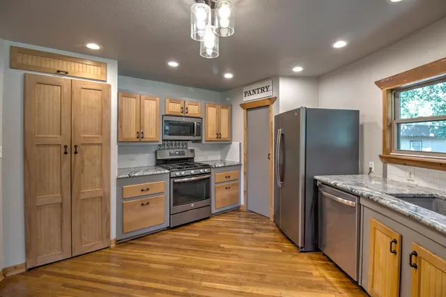 a kitchen with kitchen island granite countertop stainless steel appliances cabinets a sink and a counter top space