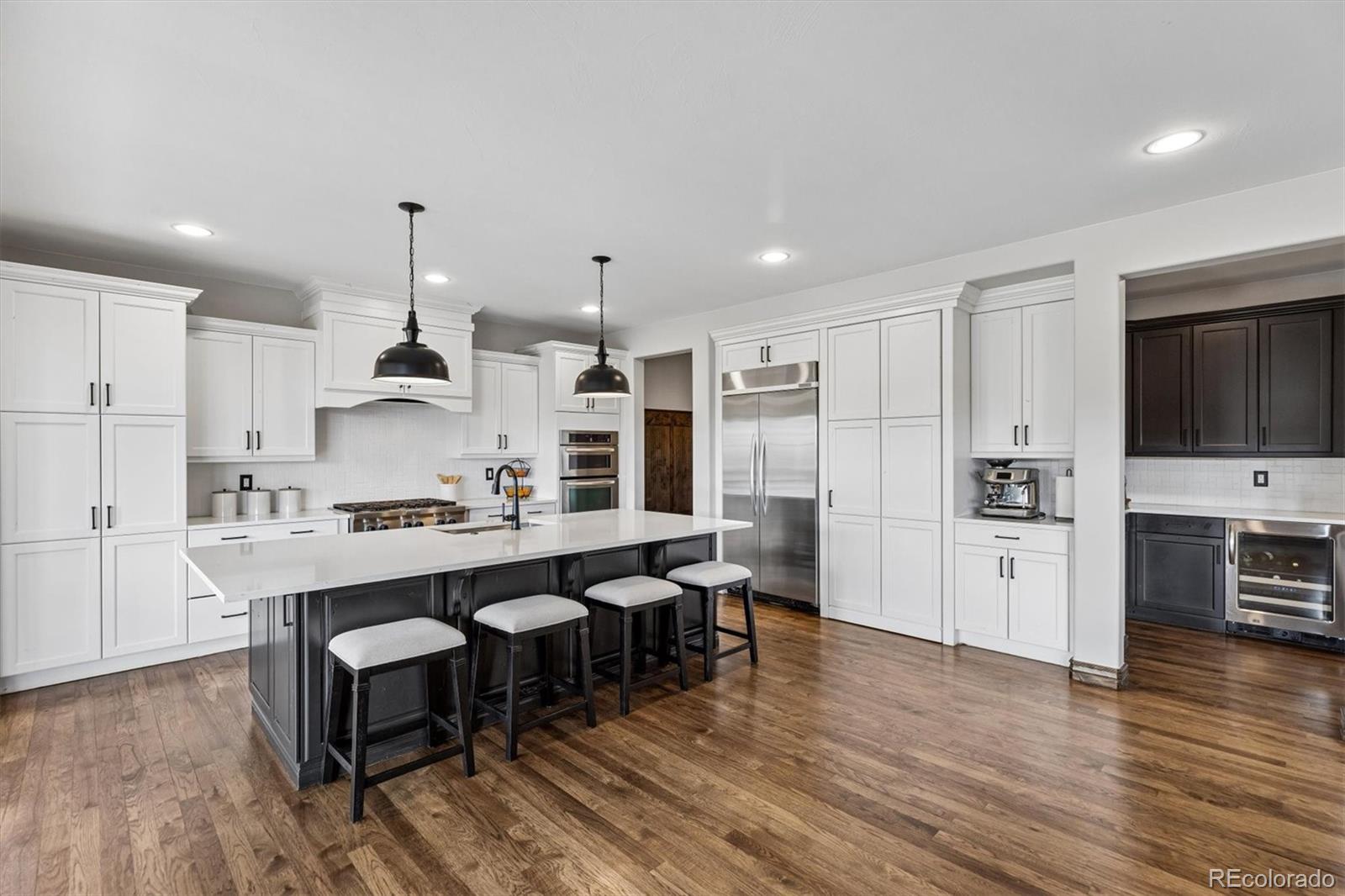 4698 Bandera Place Parker, CO 80134 - Photo 12 of 43 a kitchen with stainless steel appliances a sink a stove a refrigerator cabinets and wooden floor
