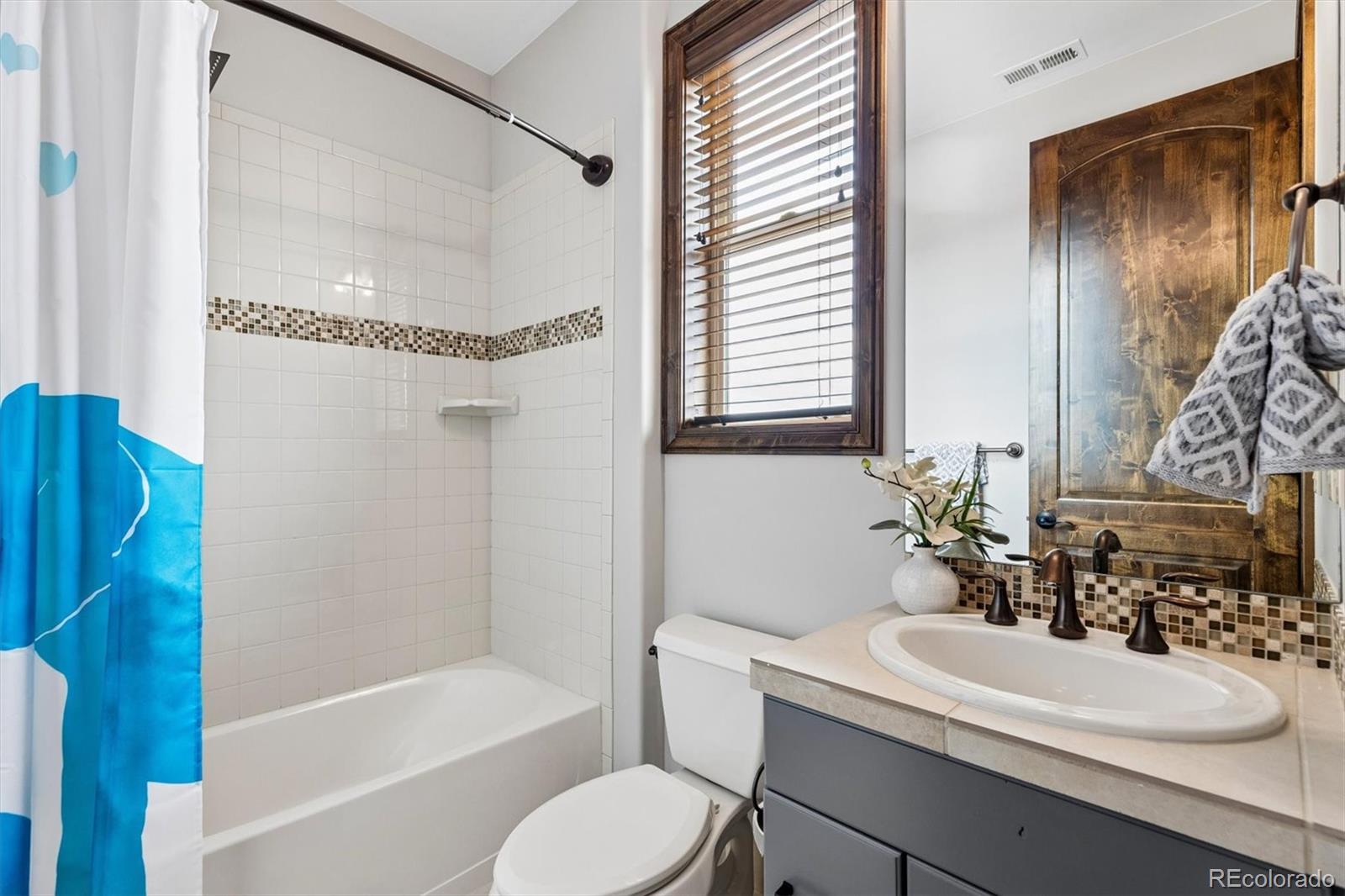 4698 Bandera Place Parker, CO 80134 - Photo 29 of 43 a bathroom with a sink a toilet a mirror and shower