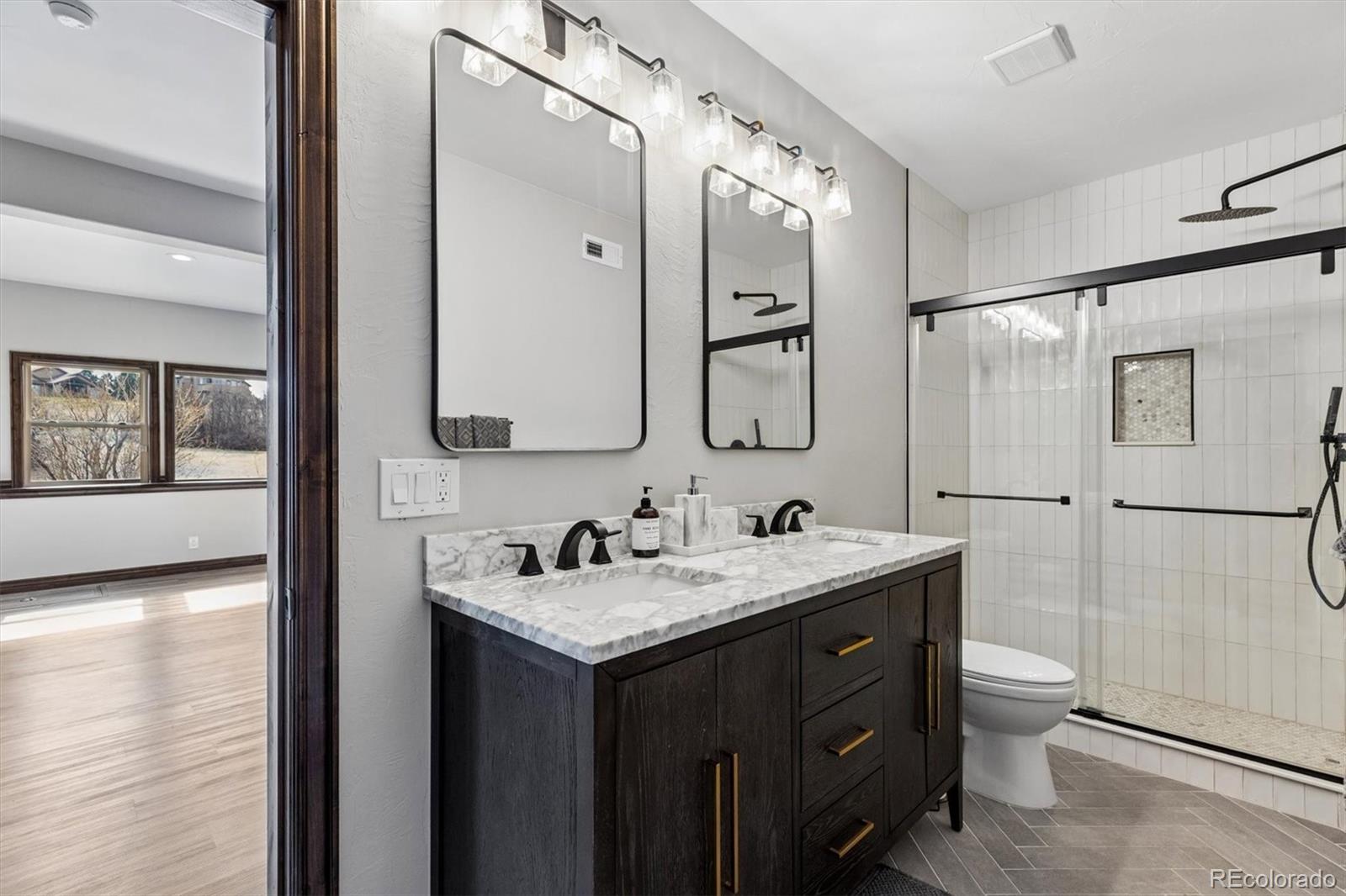 4698 Bandera Place Parker, CO 80134 - Photo 36 of 43 a bathroom with a double vanity sink toilet mirror and shower