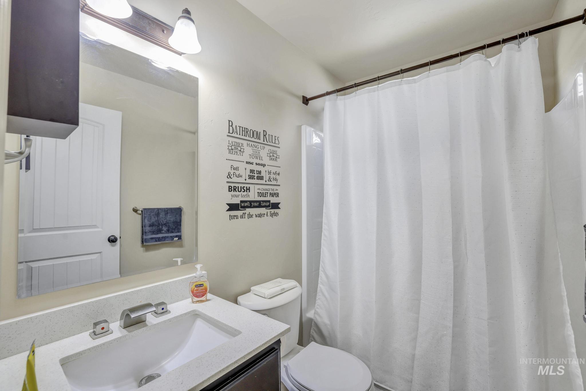 446 Noble Street Twin Falls, ID 83301 - Photo 15 of 42 Bathroom featuring a vanity with a white countertop and undermount sink, a two-light fixture, and a shower/tub combination with a white shower curtain rod