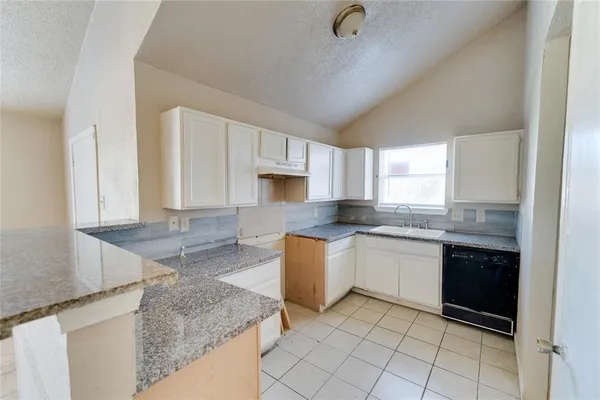 a kitchen with granite countertop a sink a stove top oven and cabinets