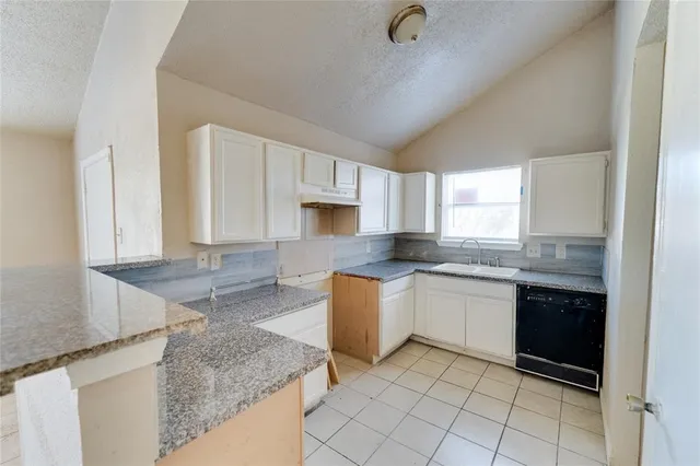 a kitchen with granite countertop a sink a stove top oven and cabinets