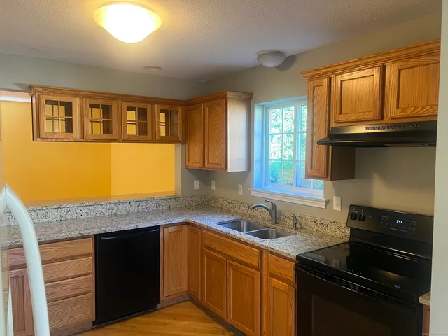a kitchen with granite countertop wooden cabinets and a stove top oven