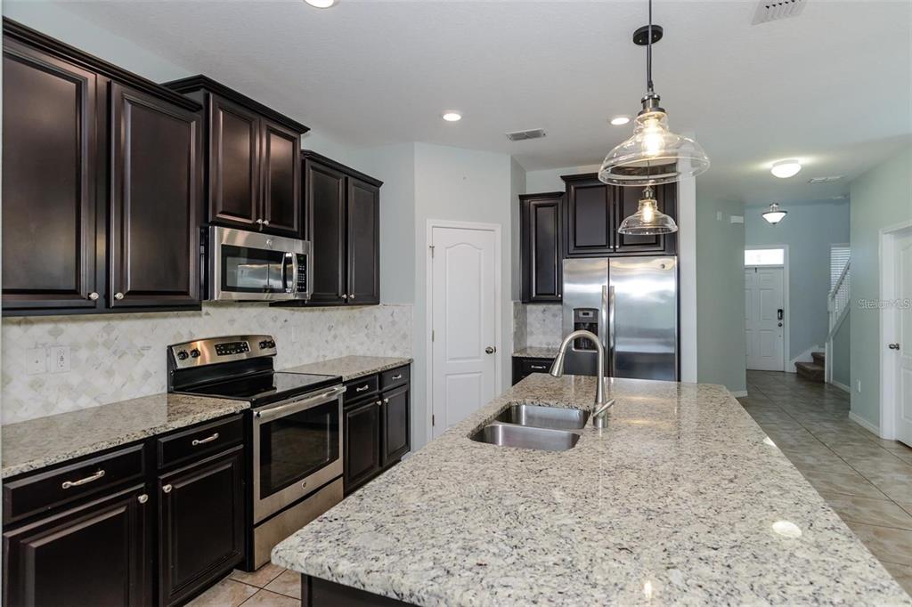 11832 Lake Boulevard New Port Richey, FL 34655 - Photo 11 of 58 a kitchen with stainless steel appliances granite countertop a sink stove and refrigerator
