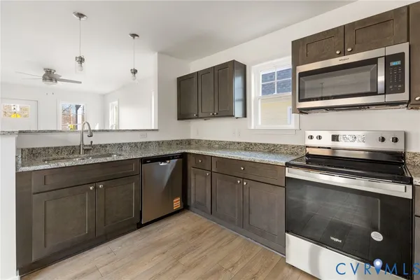 a kitchen with stainless steel appliances granite countertop a sink and a stove top oven with wooden floor