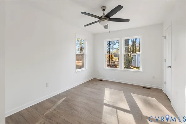 an empty room with wooden floor and windows