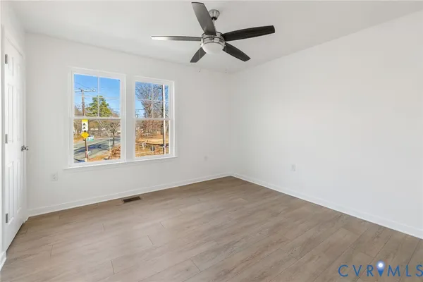 an empty room with windows and fan