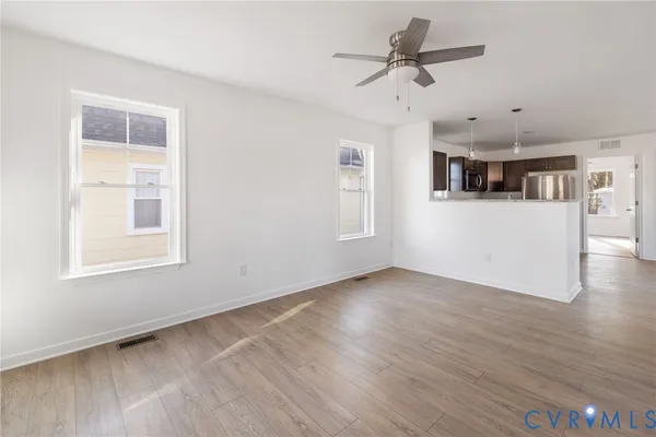 a view of an empty room with a window and wooden floor