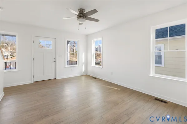 a view of an empty room with a window and wooden floor
