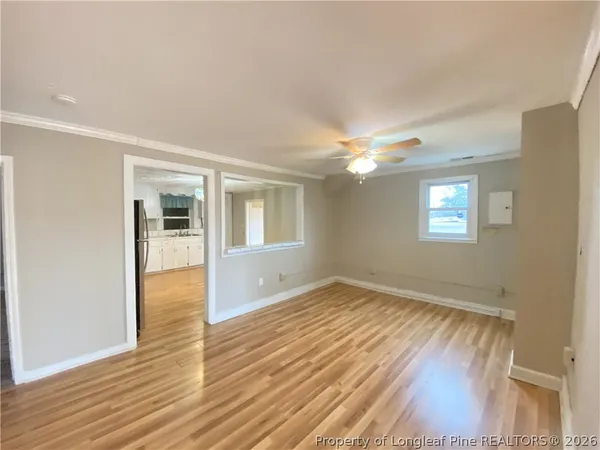 a view of an empty room with wooden floor and a window