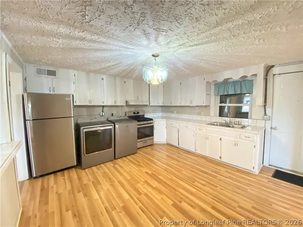 a kitchen with granite countertop a sink stainless steel appliances and white cabinets