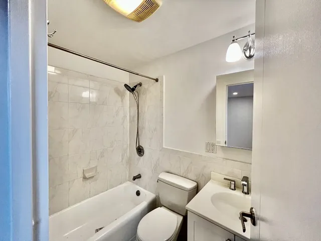 a bathroom with a bathtub shower sink mirror and toilet