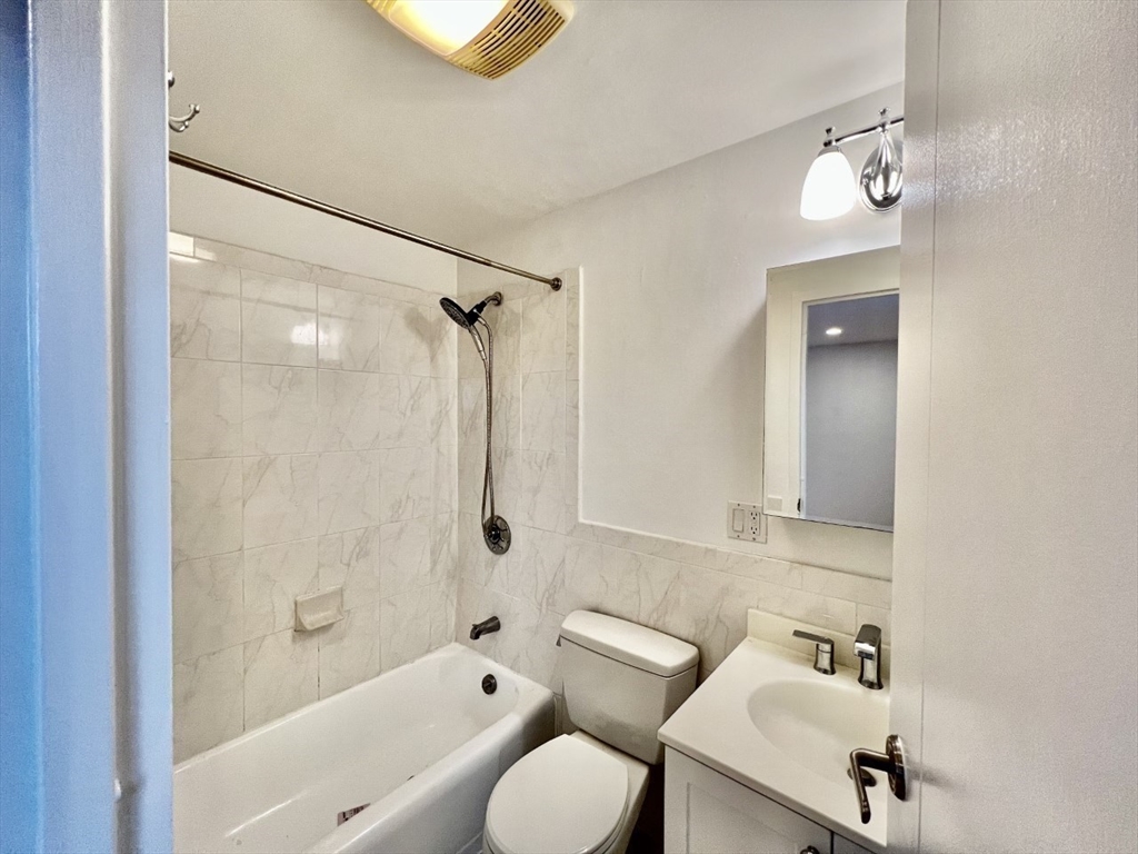 1600 Beacon Street, Unit 1002 Brookline, MA 02446 - Photo 11 of 16 a bathroom with a bathtub shower sink mirror and toilet