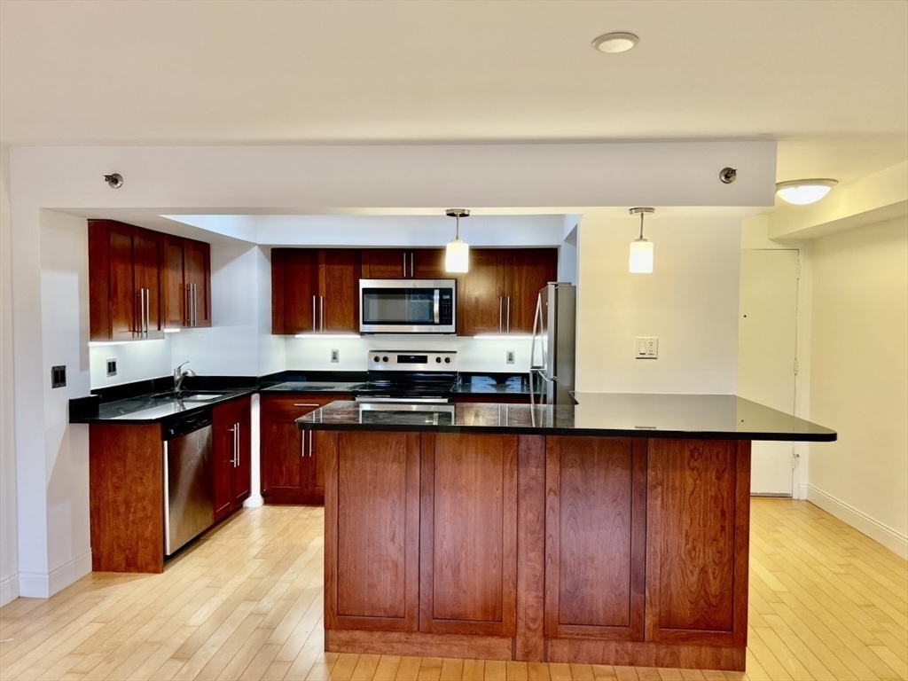 1600 Beacon Street, Unit 1002 Brookline, MA 02446 - Photo 2 of 16 a kitchen with stainless steel appliances granite countertop wooden cabinets a stove top oven a sink and dishwasher