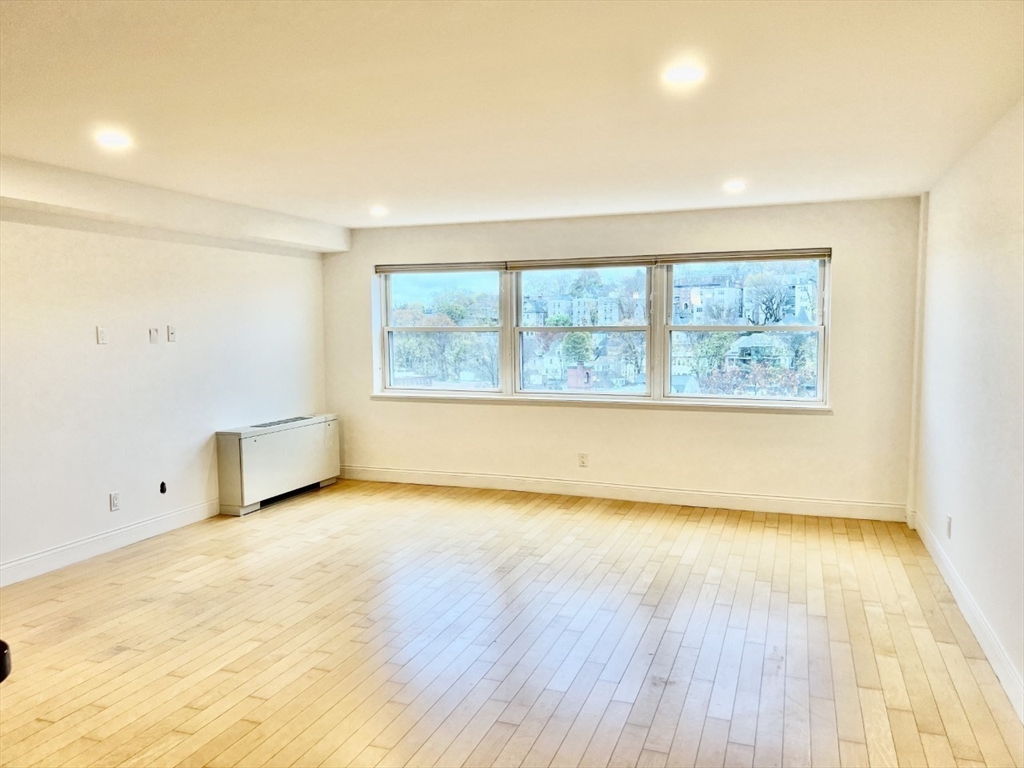 1600 Beacon Street, Unit 1002 Brookline, MA 02446 - Photo 5 of 16 an empty room with wooden floor and windows