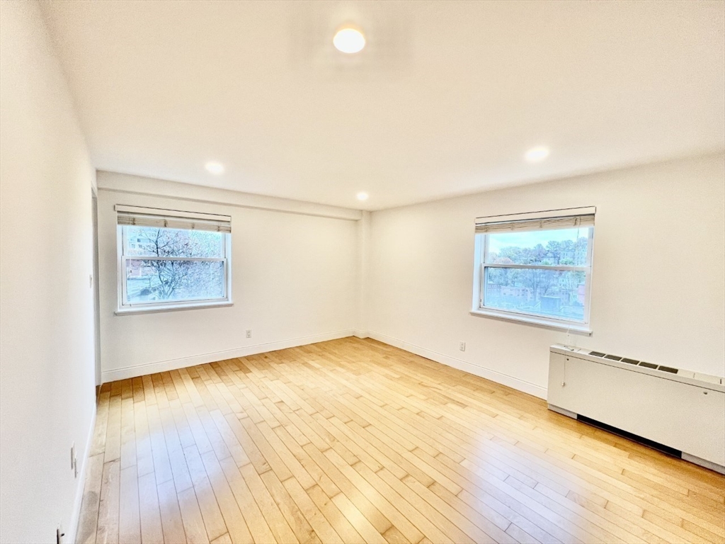 1600 Beacon Street, Unit 1002 Brookline, MA 02446 - Photo 6 of 16 an empty room with wooden floor and windows