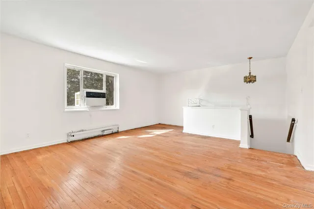 a view of empty room with wooden floor and window
