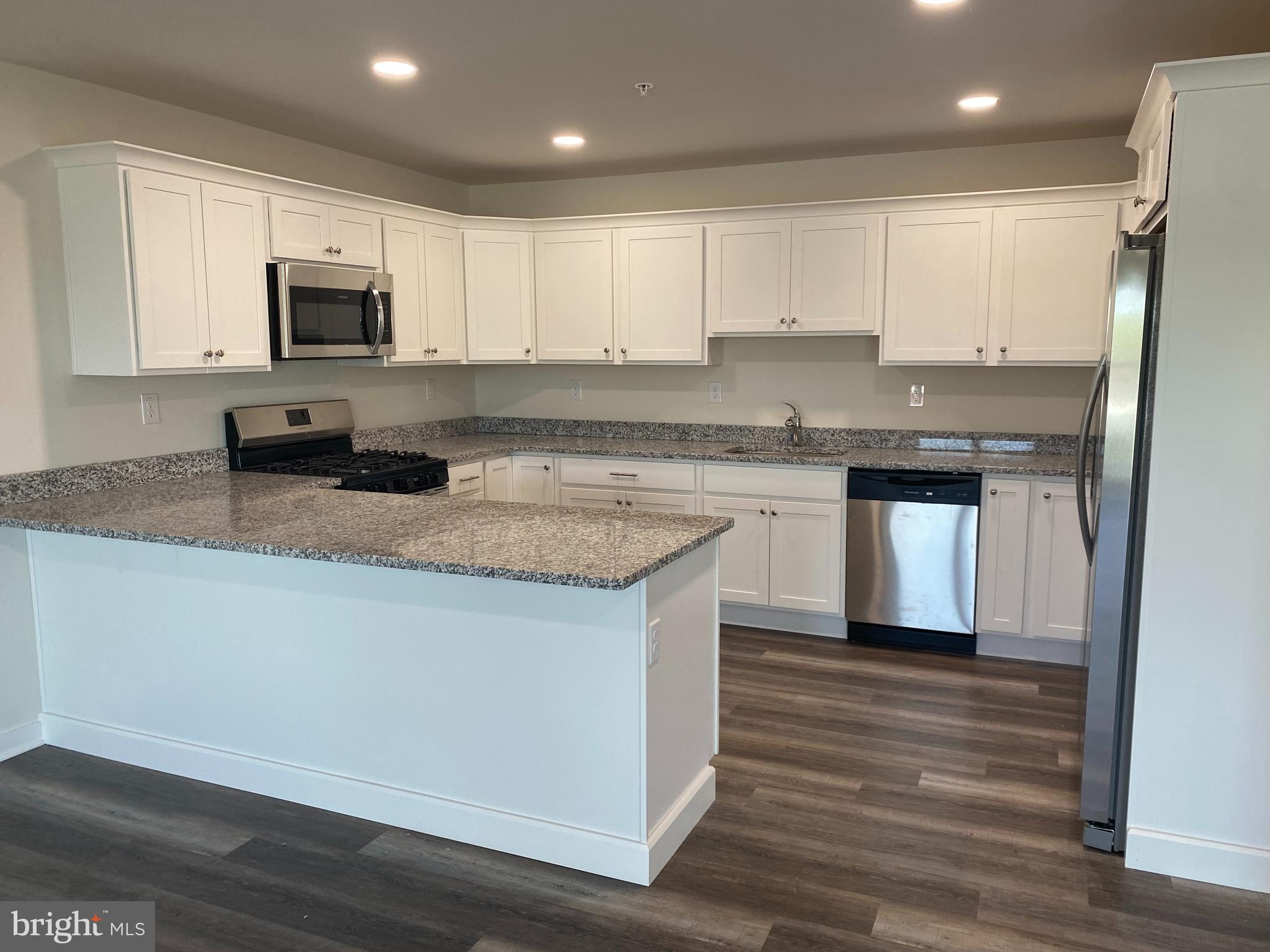 3852 Ridge Pike, Unit 3852 Collegeville, PA 19426 - Photo 9 of 24 a kitchen with stainless steel appliances granite countertop a sink stove microwave and refrigerator