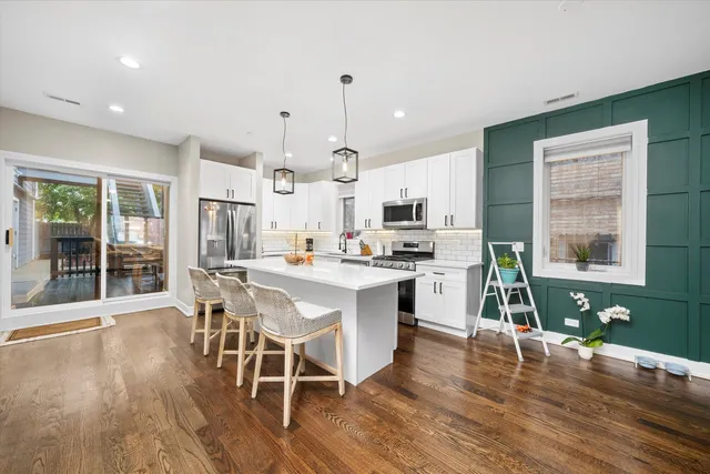 a kitchen with stainless steel appliances a dining table chairs stove and cabinets