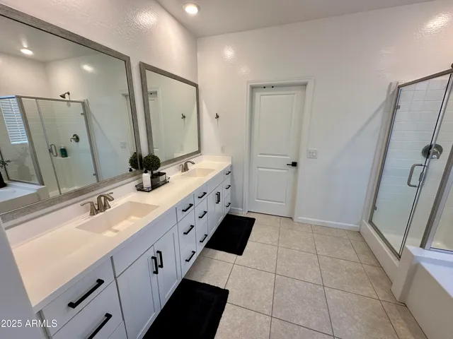 a spacious bathroom with a double vanity sink a mirror and a shower