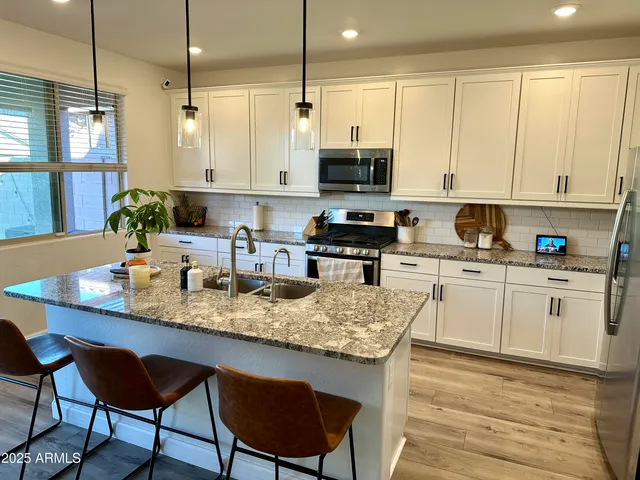 a kitchen with stainless steel appliances granite countertop a table chairs sink and cabinets