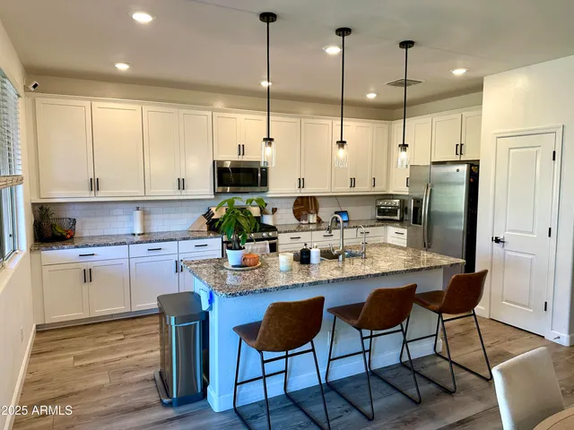 a kitchen with stainless steel appliances granite countertop a stove a sink island and a refrigerator with wooden floor