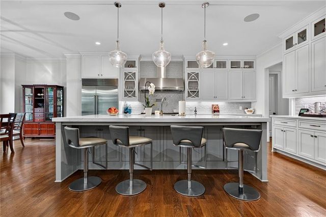 a large kitchen with stainless steel appliances kitchen island granite countertop a large counter top a stove and a refrigerator