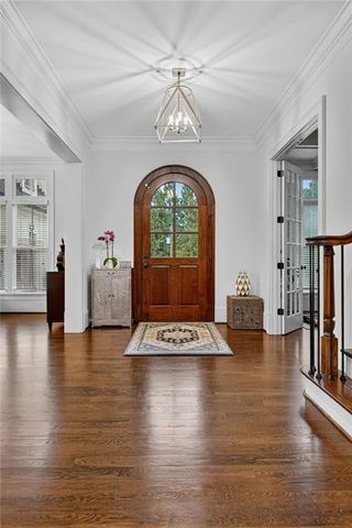 a dining room with furniture wooden floor a rug a potted plant and a chandelier