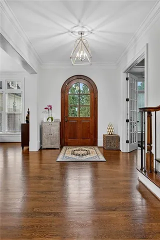 a dining room with furniture wooden floor a rug a potted plant and a chandelier