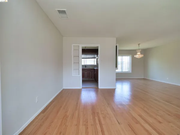 a view of empty room with wooden floor and window