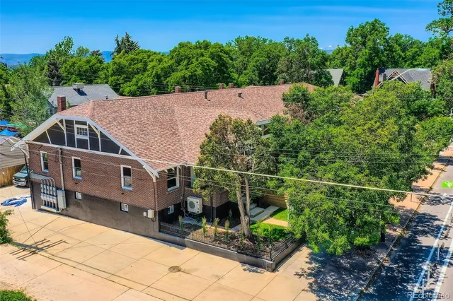 an aerial view of a house with swimming pool and trees in the background