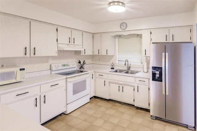 a kitchen with white cabinets and white appliances