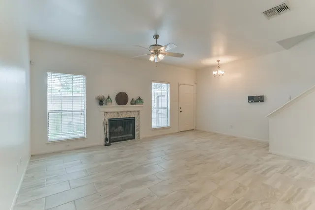 an empty room with windows and fireplace