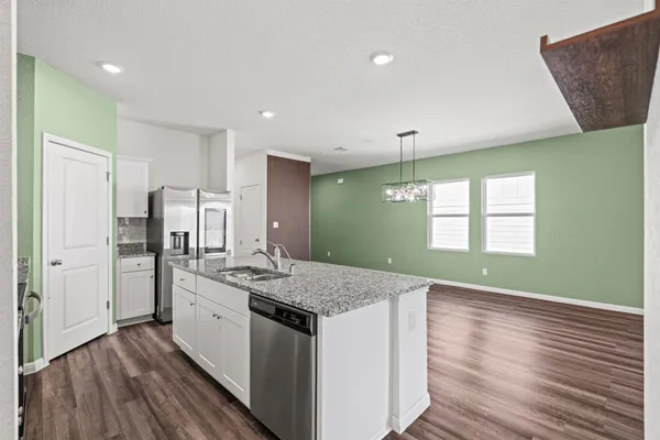 a large kitchen with stainless steel appliances granite countertop a lot of counter space and wooden floor
