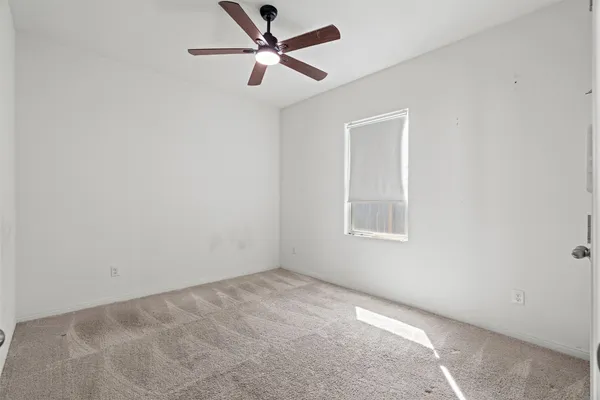 an empty room with closet and a chandelier fan