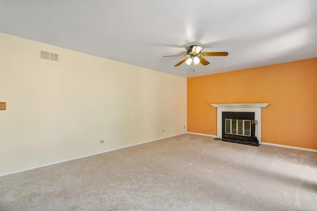a view of an empty room with chandelier fan